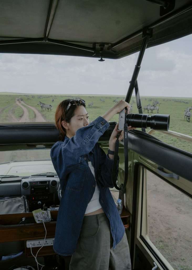Guest standing through open roof of 4x4 vehicle in Serengeti during game drive Tanzania