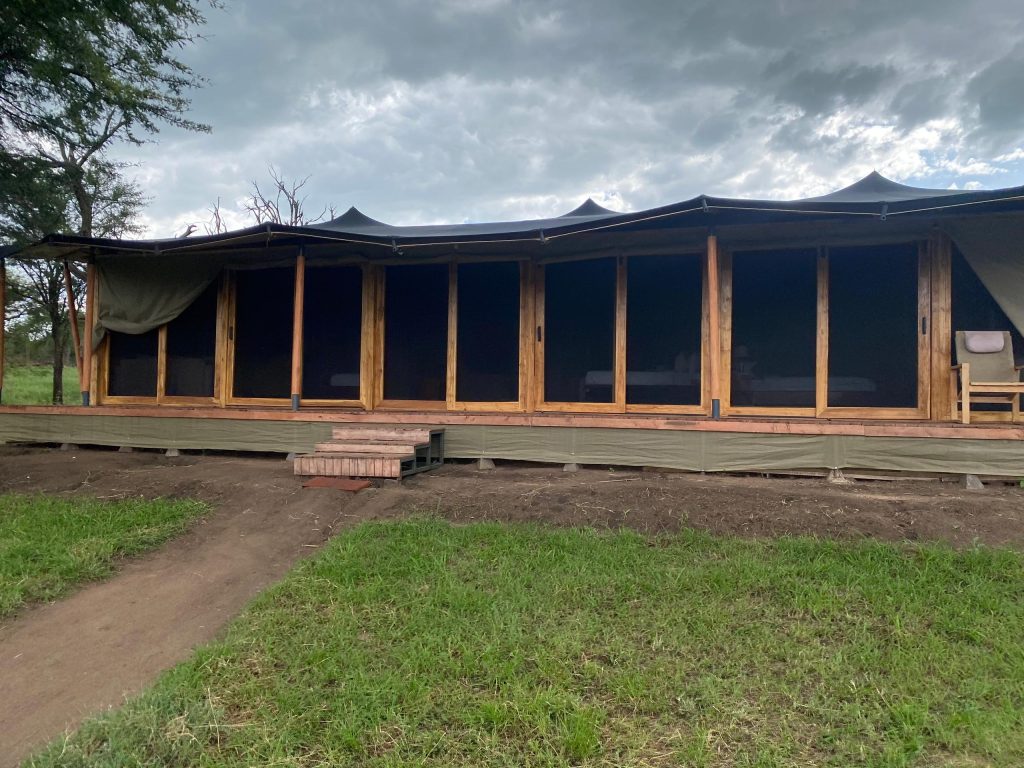 Luxury standard safari tent with wooden deck and glass sliding doors at Golden Safari Camps in Serengeti National Park.